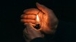 © habib - Person holding a lit cigarette lighter in cupped hands against a dark