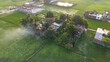 © ridwanhassan - Aerial view of a rural village in bangladesh with lush green rice fields, traditional houses, and smoke rising from a cooking fire at sunset