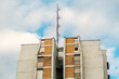 © Travel 'n' Lifestyle - View of a residential building facade with a tall antenna mast on the roof against a blue sky in Novi Sad, Vojvodina, Serbia.