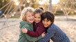 © VectorEngraveHalfton - Joyful Childhood Moments with Three Diverse Friends Hugging and Laughing at a Sunny Park Playground