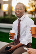 © Ljustina - Businessman smiling having coffee break outdoors
