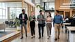 © sana - Diverse group of business professionals walking and talking in modern office