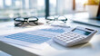 © Denis Yevtekhov - Quarterly financial report placed beside a compact white calculator on a clean office desk four quarter columns and a blue expense chart visible on the top page neatly folded