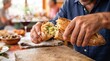 © detry26 - Man breaking crunchy garlic bread with herbs on wooden board. Appetizer at restaurant table. Homemade bakery product for dinner. Fresh crusty baguette loaf with garlic butter sauce