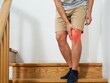 © Atick Tajwar Khan - Man standing on wooden stairs holding his painful knee with a red glowing highlight indicating injury
