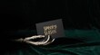 © IvanMasyudi - Bony skeleton hand holding a black Spooky Season card over dark green velvet fabric backdrop.
