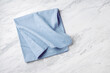 © thanksforbuying - Blue linen napkin folded on white marble table background, copy space