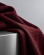 © Mai - Burgundy knitted fabric draped over brushed metal surface textile
