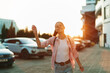 © SHOTPRIME STUDIO - A smiling woman enjoying outdoor lifestyle on a sunlit street, casual attire, carefree mood. Bright backlight and urban ambiance create a warm, vibrant portrait of everyday happiness.