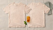 © Anim - Two light beige t-shirts laid flat on a textured fabric surface with a glass of iced tea and fresh green mint leaves placed in the center