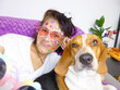 © D.Petrus - selfie of a Middle eastern mature woman wearing colorful stickers on her face with her beagle dog looking at camera