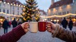 © Pavel - Close-up of two people holding and toasting steaming ceramic mugs at a glowing European Christmas market with a decorated tree and lights in the background.