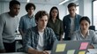 © Vadym - Diverse young startup team watches video call on laptop in open plan office. Group of junior employees shows shock, concern after business announcement. Colleagues react to pivot news with anxiety,