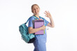 © Alliance - A smiling young woman in blue medical scrubs waves while holding study notebooks and a stethoscope, representing a welcoming start to a healthcare career.