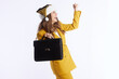 © Alliance - A businesswoman in a yellow suit and festive Santa hat raises her fist in triumph, holding a briefcase against a white background, symbolizing holiday success and achievement.