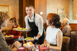 © JackF - Guy waiter serves cafe establishments couple visitor, puts food on table. Restaurant employee delivers food to guests, communicates nicely, wishes them pleasant appetite..