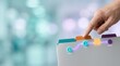 © KohXD - Person holding piece of paper in blank medical referral folder with colored edge tabs for healthcare coordination