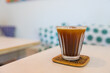 © leungchopan - Iced coffee glass on woven coaster placed on cafe table