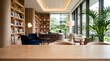 © Nest - Wooden table surface in foreground with blurred sunlit lounge area interior background featuring comfortable armchairs and library bookshelf wall