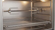 © Vera - Cleaning inside of rotisserie oven with metal components and rack