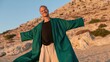© navisatul - Man in flowing robe smiles with open arms on sandy terrain.