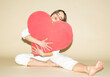 © VISTA by Westend61 - Woman in white jumpsuit hugging large red heart symbolizing love
