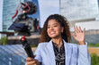 © BusinessClass by W61 - A smiling businesswoman waves and films a video in the city
