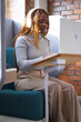 © WavebreakMediaMicro - African woman in 30s working on laptop on wooden stand in teal booth, wearing headphones
