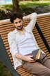 © LIGHTFIELD STUDIOS - Charming young man enjoys a sunny day while reading outdoors in the city