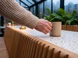 © AdPremium - Person wearing a warm knitted sweater holding a ceramic coffee mug on a terrazzo table in a cozy modern cafe greenhouse