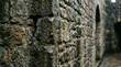 © Aether Pixels - Closeup of a weathered dark stone wall with an arched opening beyond it