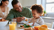 © Nataliya - Father feeding a toddler during a healthy family breakfast in a bright kitchen, mother smiling nearby, parenting, early childhood nutrition, family bonding, wholesome lifestyle,