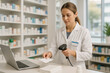 © thodonal - Pharmacist scanning a medicine box beside a laptop