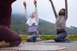 © WavebreakMediaMicro - Three African American women stretching on wooden deck with yoga mats, teal bottle, layered jackets