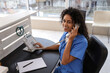 © Pixel-Shot - Healthcare administration and patient support, smiling nurse or medical receptionist talking on office phone at hospital reception desk with stethoscope