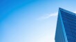 © AspctStyle - Modern glass skyscraper corner against a clear blue sky, capturing architectural innovation and corporate success for commercial real estate marketing and professional business presentation.