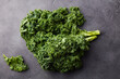 © annapustynnikova - Raw curly kale cabbage heads on dark grey stone kitchen table. Grey background. Close up. Top view.