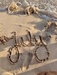 © Stephanie - July written in sand on a Caribbean beach with ocean waves