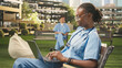 © DC Studio - Focused medical student in blue scrubs types on a laptop with a stethoscope nearby, taking notes and studying on a bench on a modern campus during a medical school training session.