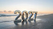 © creativestore - Metallic silver 2027 numbers standing on a beach shore during a peaceful sunrise with new year