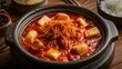 © Sesar Journey - Kimchi jjigae, a Korean spicy stew with pork, tofu, vegetables, and fermented kimchi in a rich red broth, served with steamed rice and side dishes on marble.