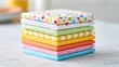© Anat art - A stack of six neatly folded cocktail napkins in various patterns and colors sits on a marble surface. Bright light adds a cheerful look.