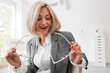 © Pixel-Shot - Vision correction and eye health, happy woman holding new prescription glasses in an optometrist office for a clear sight and ophthalmology checkup