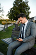 © Marko - Businessman sitting on bench looking stressed while using tablet