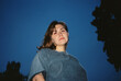 © Asya Molochkova/Stocksy - Young woman portrait looking up against blue evening sky