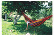 © Ivan Haidutski/Stocksy - Girl leaning out of a colorful hammock under trees in the garden