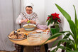 © pundapanda - In a kitchen in Ukraine, a woman is making kholodets, aspic, or jellied meat. She grates garlic into a bowl of broth. On the table, there are other ingredients and containers for the dish