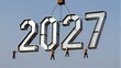 © joeycheung - Workers hoist massive 2027 numerals against clear sky, symbolizing new year's arrival.