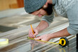 © peopleimages.com - Carpenter, man and measuring tape on glass in workshop for DIY project, handicraft and production. Handyman, person and marking material for carpentry, furniture restoration and creative remodeling
