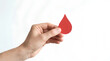 © Golden Eagle - Hand holding a red paper drop symbolizing blood donation or health awareness, isolated on a plain white background for visual